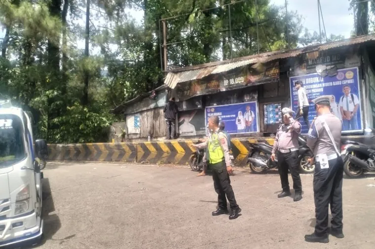Petugas kepolisian berjibaku mengatur lalu lintas di jalur ekstrem Sitinjau Lauik, Padang, saat kemacetan parah menyebabkan ribuan kendaraan terjebak selama dua hari. (Foto: Ist)