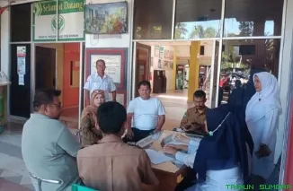 Petugas RSUD M. Zein Painan membantu pasien menggunakan aplikasi Mobile JKN. (Foto: Ist)