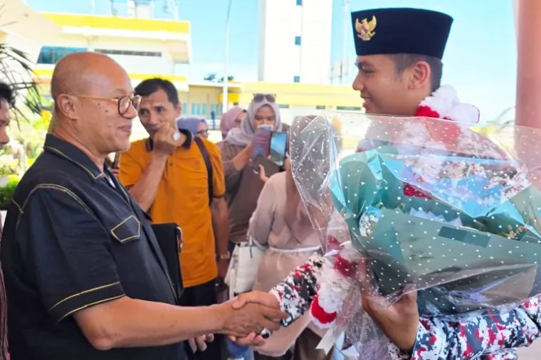 Ketua Umum DPW PKPS Sumbar, H Budi Syukur Dt Bandaro Jambak, mengalungkan bunga kepada Habib Burhan, siswa SMAN 1 Pancung Soal yang sukses bertugas sebagai Danru 17 Paskibra Nasional di Istana Negara. (Foto: Ist)