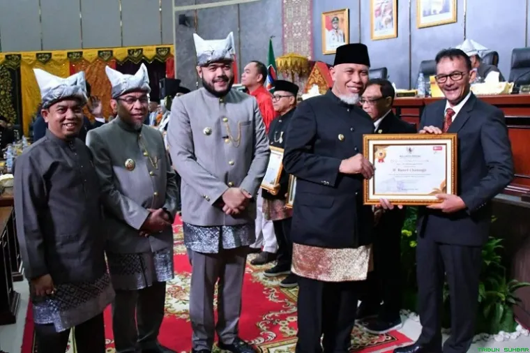 Gubenur Sumbar Mahyeldi serahkan piagam penerima pin emas kepada tokoh pers Hasril Chaniago didampingi Walikota, Wawako dan Ketua DPRD Padang. (Foto: Ist)