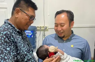 Anggota Komisi IV DPR RI, Rahmat Saleh, menggendong Aksara Diksi Yr saat kunjungan ke kediaman Boban Yr di Jalan Andalas, Padang, Sabtu (18/10/2025). (Foto: Ist)