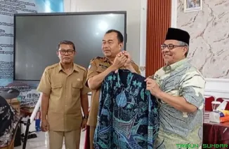 Ketua DPRD Sumatera Barat, Muhidi, menyerahkan secara simbolis setelan baju batik kepada Kepala SMA Negeri 10 Padang, Muhammad Isya. (Foto: Ist)