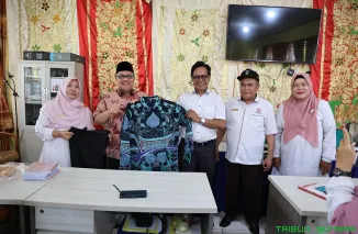 Ketua DPRD Sumbar Muhidi menyerahkan bantuan batik kepada guru SMA Negeri 8 Padang, Rabu (15/10/2025). (Foto: Ist)