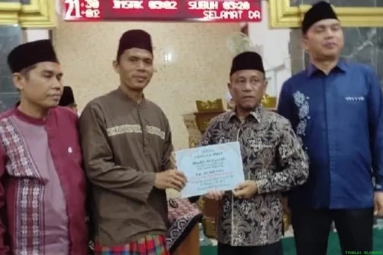 H. Rusdi menyerahkan bantuan kepada pengurus Masjid Al Quwait saat Safari Ramadan di Banuaran Nan XX, Kecamatan Lubuk Begalung, Kota Padang, Senin malam (23/2/2026). (Foto: Ist)