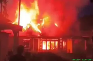 Petugas pemadam kebakaran bersama warga memadamkan api yang melahap rumah di Jorong Labuah Luruih, Sungai Kambut, Dharmasraya, Rabu malam (25/3/2026). (Foto: Ist)