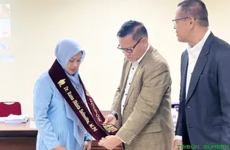 Dr Rama Shinta Safmelita, SPd, MPd (tengah), karateka peraih gelar Doktor dari Pasca Sarjana Fakultas Ilmu Keolahragaan (FIK) Universitas Negeri Padang (UNP), menunjukkan ijazah usai mengikuti sidang promosi doktor di Padang, Kamis (21/5/2026). (Foto: Ist