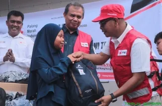 Ketua PMI Sumbar Aristo Munandar menyerahkan paket School KIT secara simbolis kepada salah satu anak korban bencana di Huntara Taratak Baru, Bayang Utara, Pesisir Selatan, Senin (1/6/2026). (Foto: Ist)