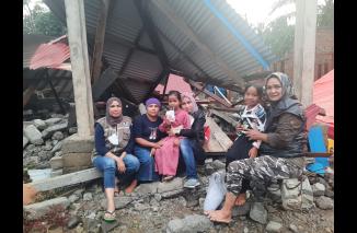 Korlap Aksi Kemanusiaan TOP 100 Sari Lenggogeni (memangku anak, tengah) Bundo Wati (kanan) dan Mona Sisca bersama korban yang rumahnya rata dengan tengah di Kampung Taruko, Jumat 4 Maret 2022. (dok)