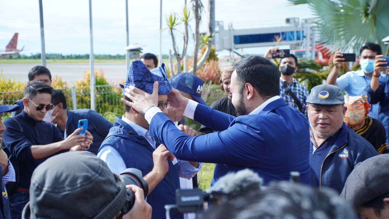Ketua DPW Partai NasDem Sumbar Fadly Amran pasangkan Deta ke kepala Anies Baswedan setelah Capres Partai NasDem  mendarat di BIM, Sabtu 3 Desember 2022. (dok) 'Assalammualaikum Sumatera Barat,: ujar Anies Baswedan sambut salam rakyat dan dengar teriakan A