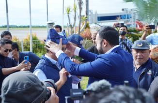 Ketua DPW Partai NasDem Sumbar Fadly Amran pasangkan Deta ke kepala Anies Baswedan setelah Capres Partai NasDem  mendarat di BIM, Sabtu 3 Desember 2022. (dok) 'Assalammualaikum Sumatera Barat,: ujar Anies Baswedan sambut salam rakyat dan dengar teriakan A