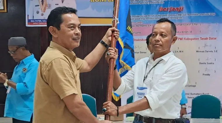 Teks Foto : Ketua PWI Sumbar Widya Navies (kiri) menyerahkan bendera PWI ke Ketua PWI Tanah Datar terpilih, Chandra Antoni, Sabtu (25/10/2025). IST